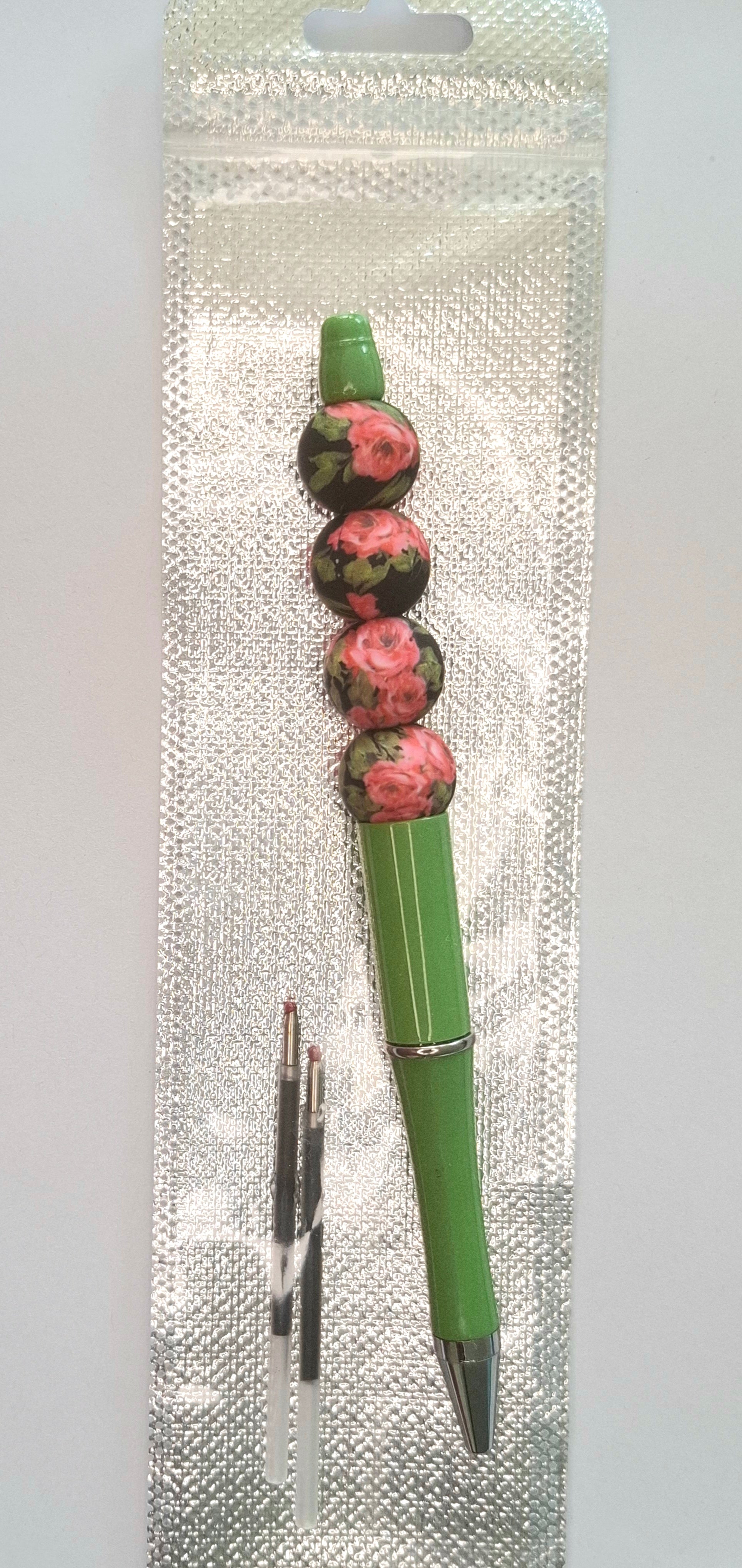 Stylo vert à fleurs roses